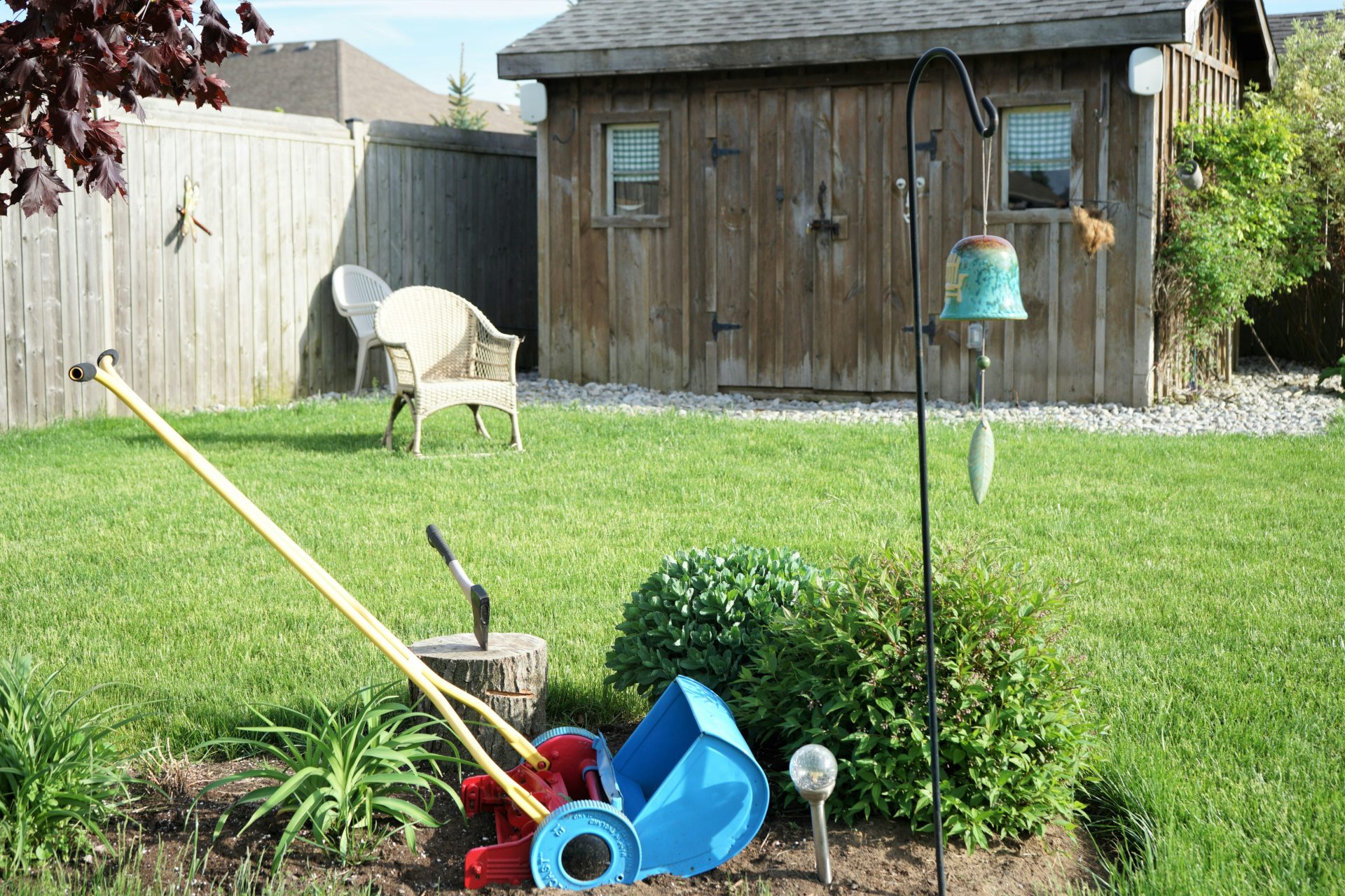 a yard with a lawn mower, garden tools and a birdhouse